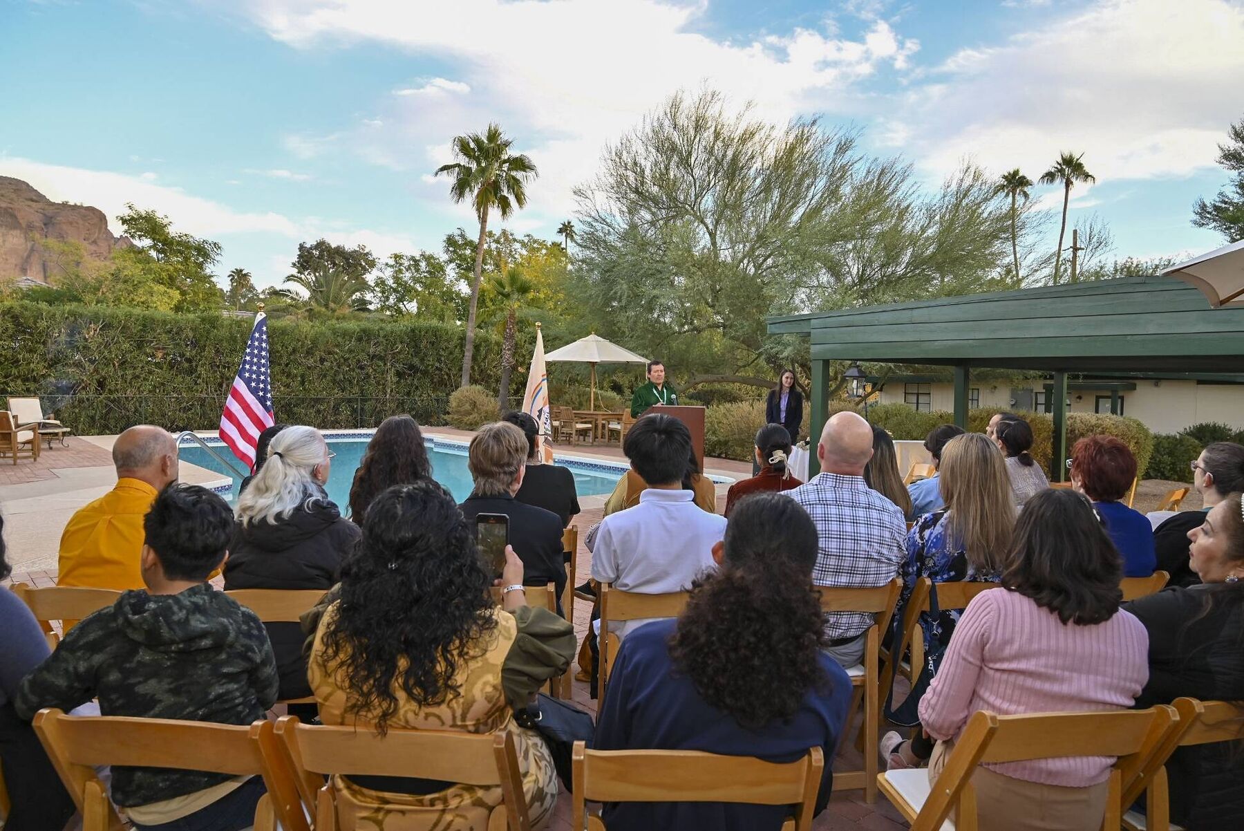 A seated audience outdoors, listening