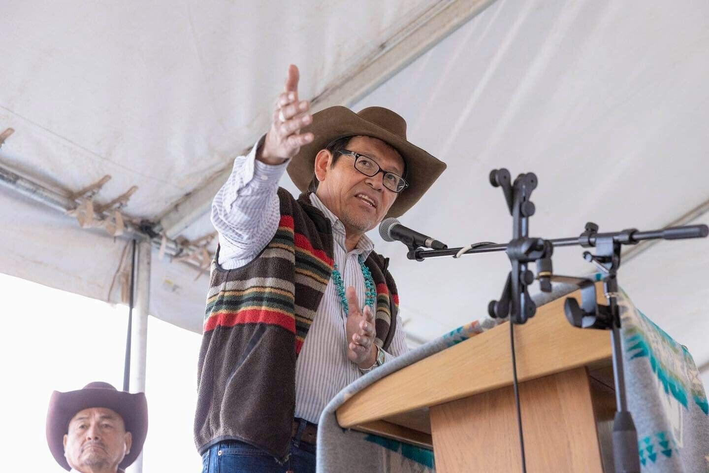 At the podium under an open tent