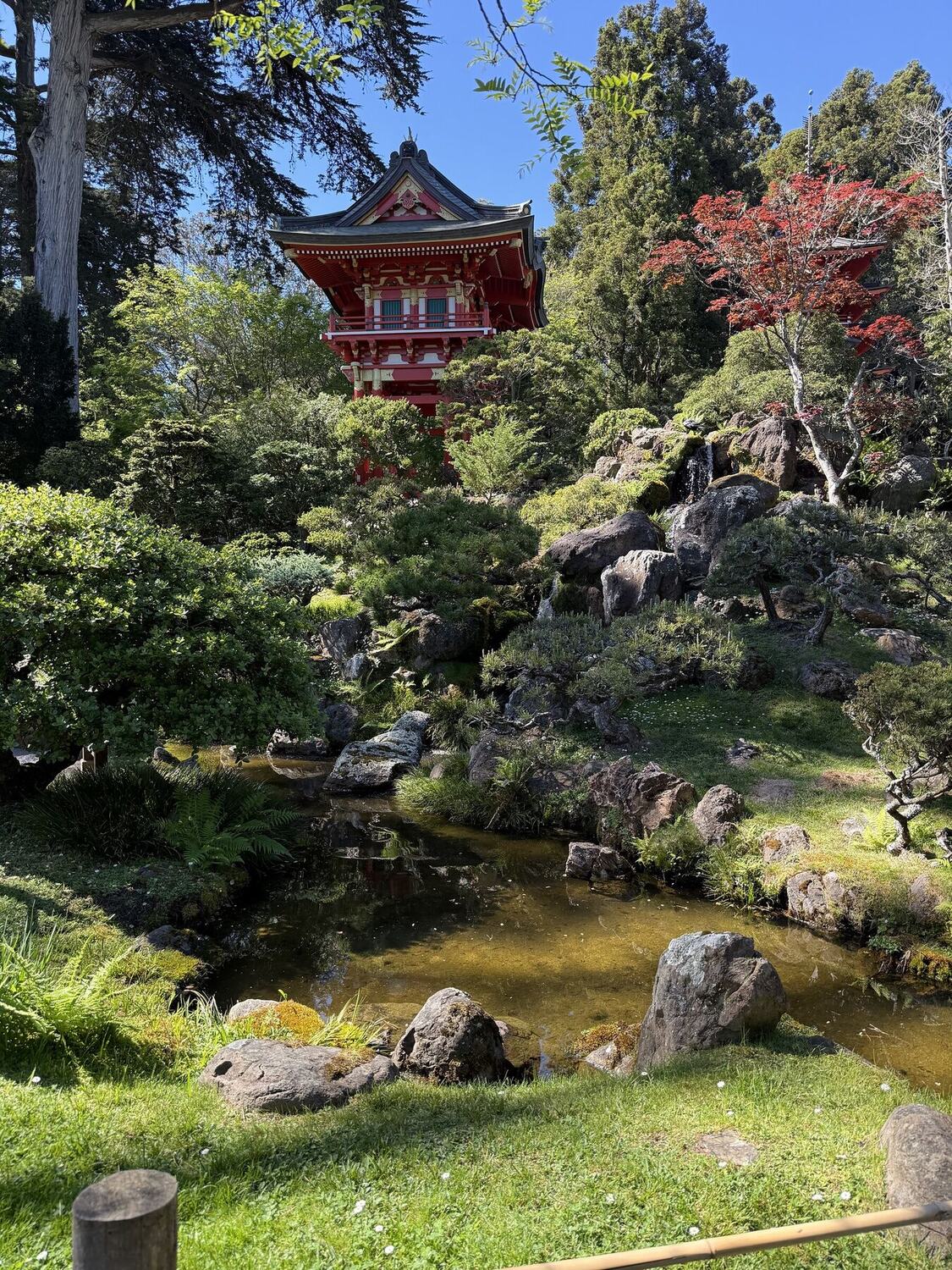 A pagoda standing above a clipped garden and pond